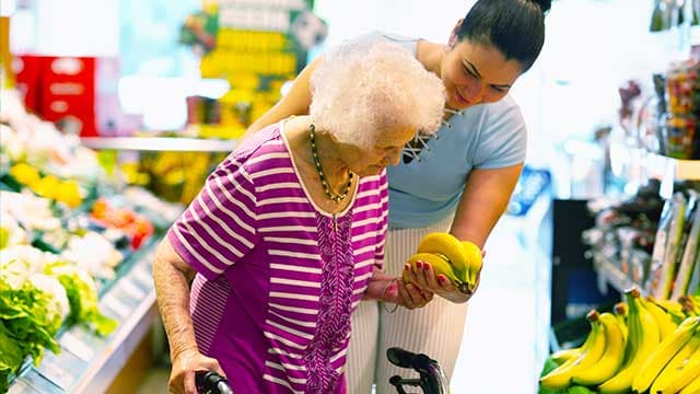 Une auxiliaire de vie aide une personne âgée dans ces courses