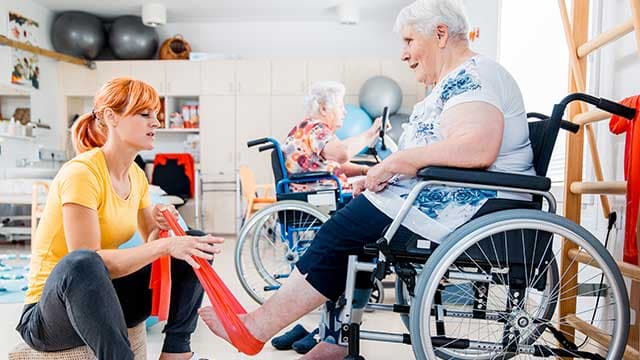 Une auxiliaire de vie aide une personnes en fauteuil lors d'une séance de sport